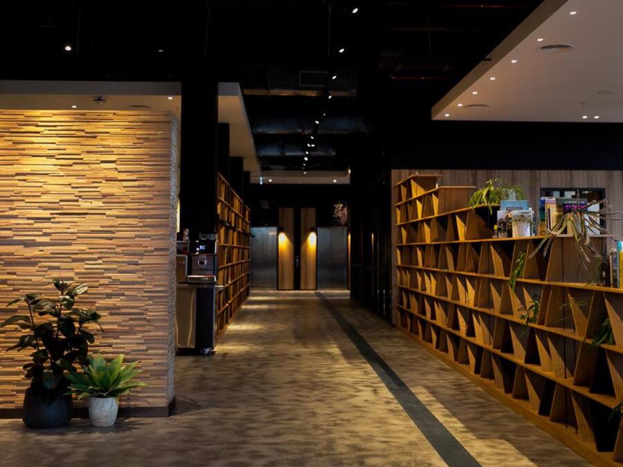 A corridor with wooden paneling on the walls, a reception desk, and potted plants.