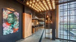 A modern interior with a large abstract painting, exposed ceiling beams, and hanging light fixtures.