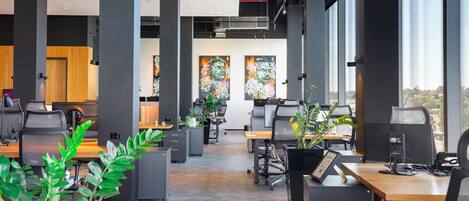 A modern office space with desks, chairs, and large windows.