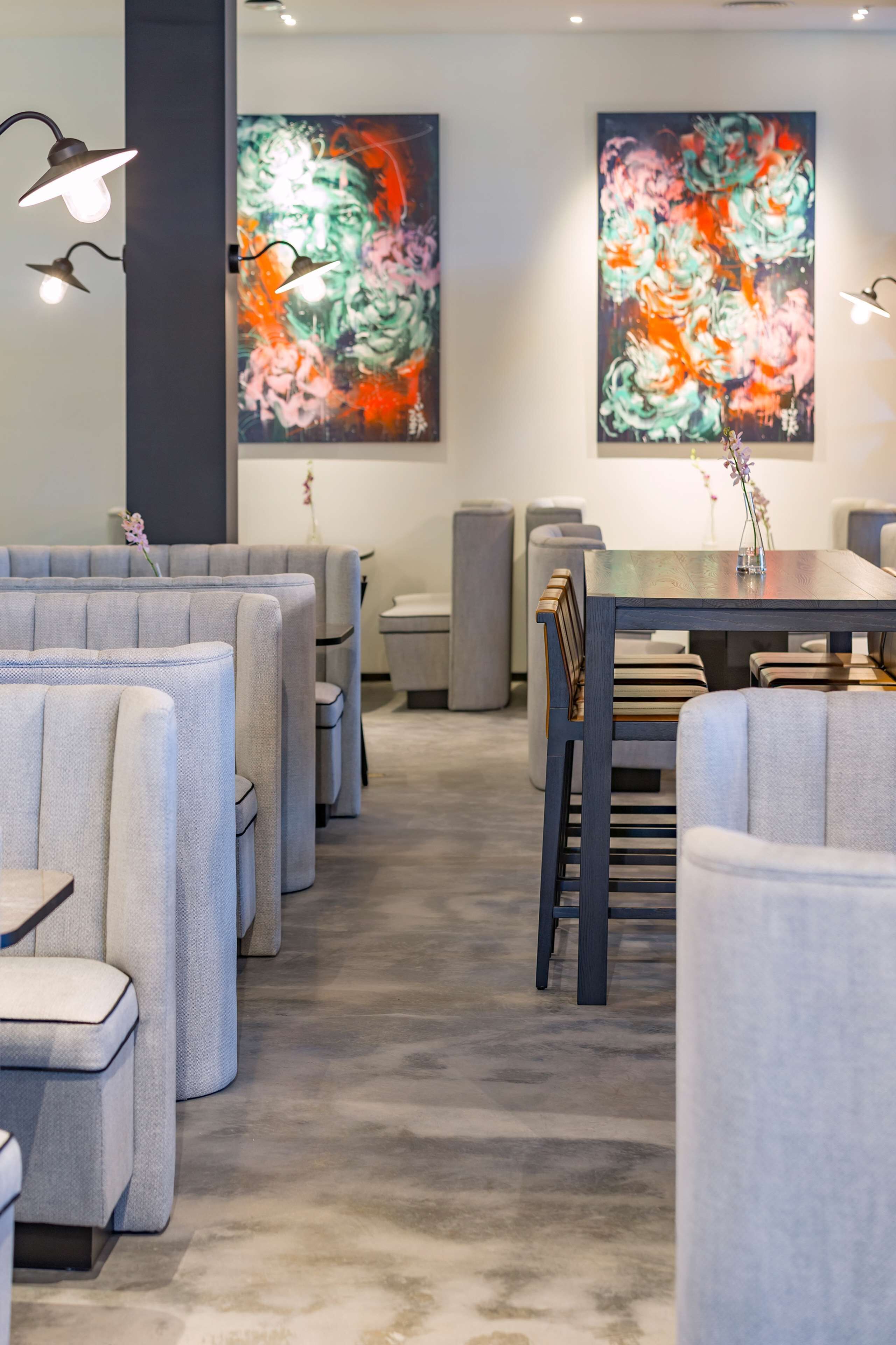 Un restaurante moderno con cabinas tapizadas en gris y una mesa de comedor de madera.