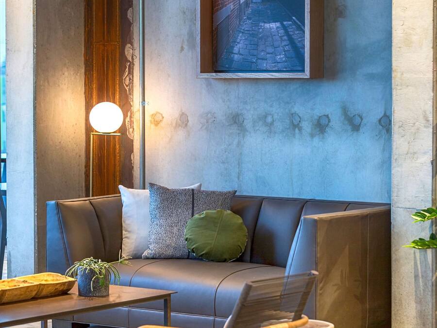 Een moderne woonkamer met een bank, een salontafel en een stoel. Aan de muur hangt een schilderij en er staat een vloerlamp.