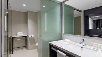 A modern bathroom with a glass shower enclosure, a white sink, and a large mirror.