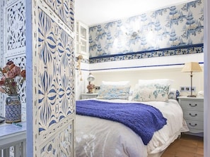 A bedroom with a bed, nightstands, and a decorative wall with blue and white patterns.