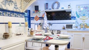 Een moderne keuken met een eethoek, met een betegelde achterwand in wit en blauw, een magnetron en een spoelbak.
