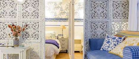A bedroom with a bed, bedside table, lamp, and decorative panels.