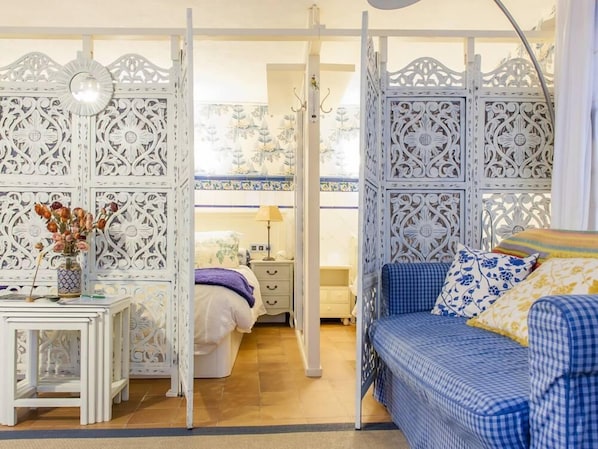 A bedroom with a bed, bedside table, lamp, and decorative panels.
