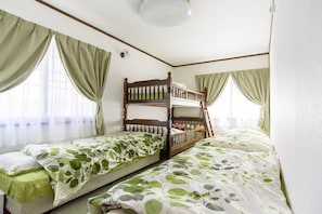 Ein Zimmer mit zwei Etagenbetten, einem Vorhangfenster und einer Deckenleuchte.
