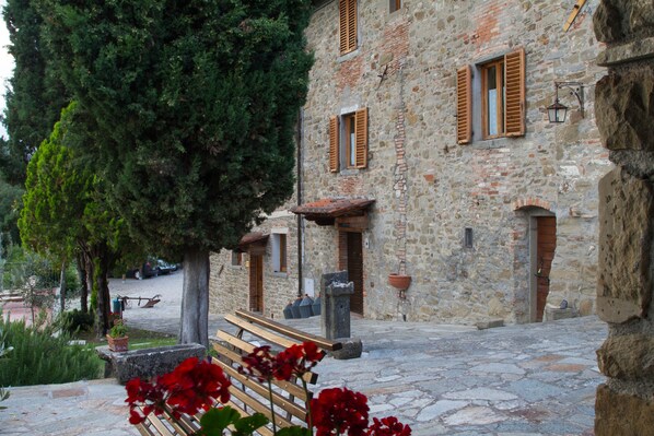 A stone building with wooden shutters, a bench, and a tree in front. - Romantic detached cottage with pool, in a farm between Arezzo and Florence (PRATOVECCHIO)