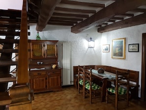 A dining area with a wooden table and chairs, a cabinet with glass doors, and a staircase.
