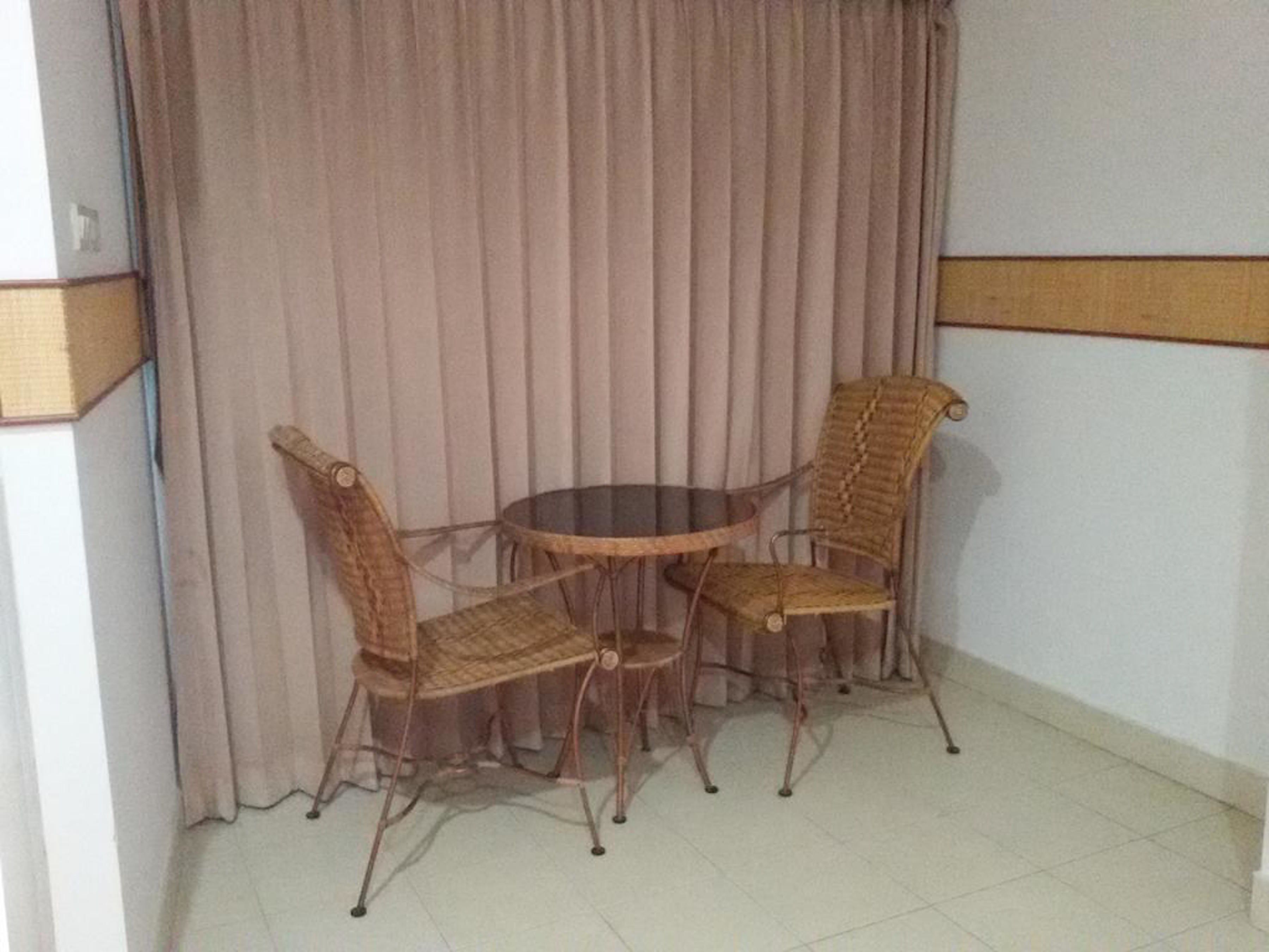 A corner room with a round table and four wicker chairs.