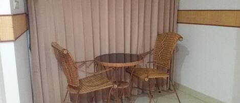 A corner room with a round table and four wicker chairs.