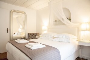 Ein Hotelzimmer mit einem großen Bett, einem Baldachinbett, einem Spiegel und Nachttischlampen.