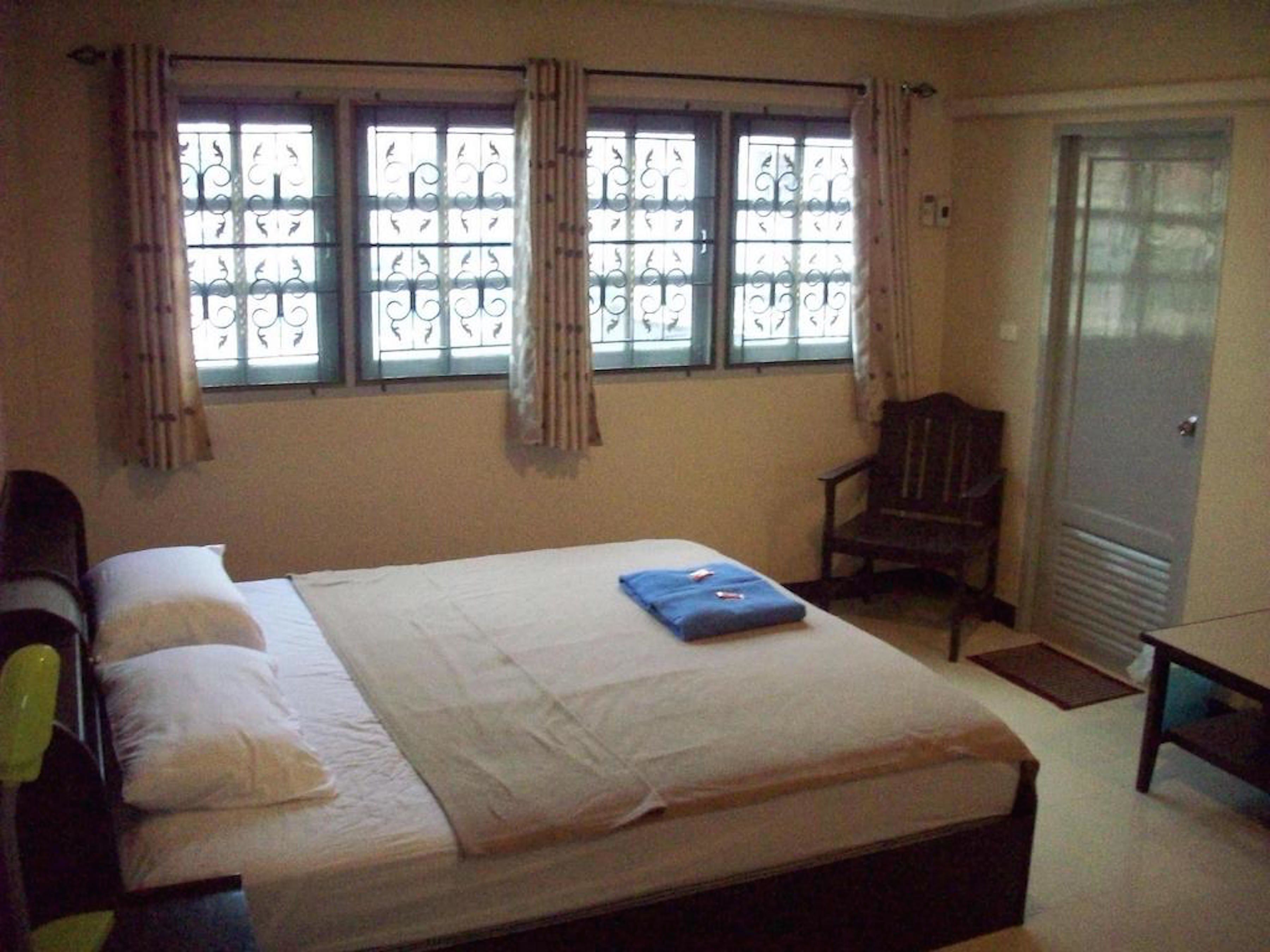 A bedroom with a bed, a chair, and a wardrobe.