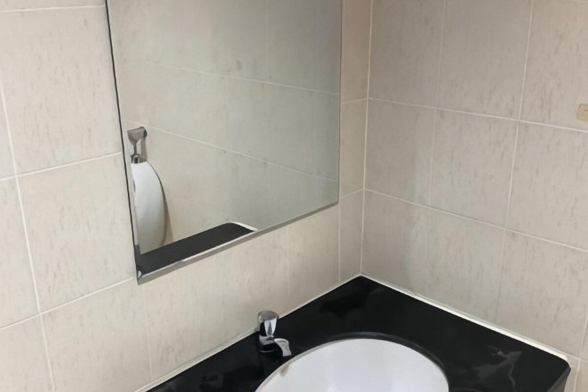 A bathroom with a black sink, a mirror, and beige tiled walls.