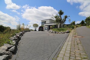 A paved pathway leading to a modern building with a car parked nearby.
