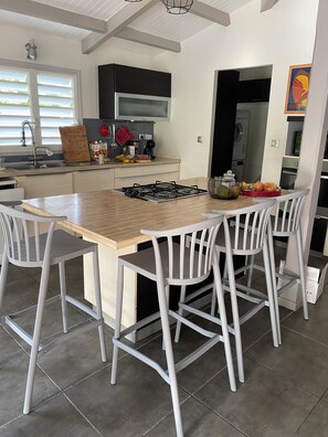 Une cuisine moderne avec un îlot central, des tabourets de bar blancs et une table à manger.