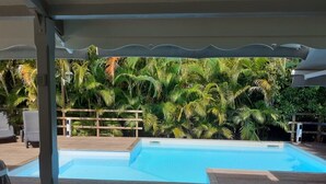 A swimming pool with a wooden deck and a covered area. - Cozy and modern charming villa 5 minutes walk from the beach (Le Gosier)