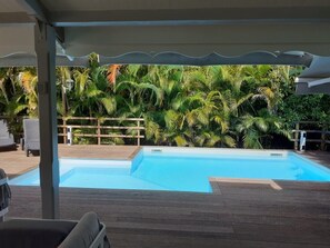 A swimming pool with a wooden deck and a covered area.