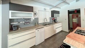 A modern kitchen with white cabinetry, a dishwasher, a sink, and a stove. - Cozy and modern charming villa 5 minutes walk from the beach (Le Gosier)