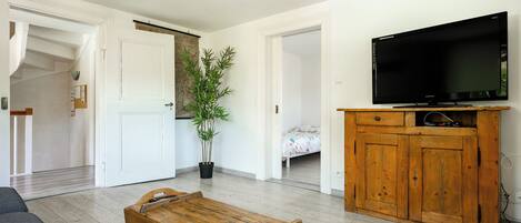 A living room with a television, wooden cabinet, and a potted plant.