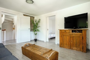 A living room with a television, wooden cabinet, and a potted plant. - Apartment Garden and Mountain View (Breitenbach-Haut-Rhin)