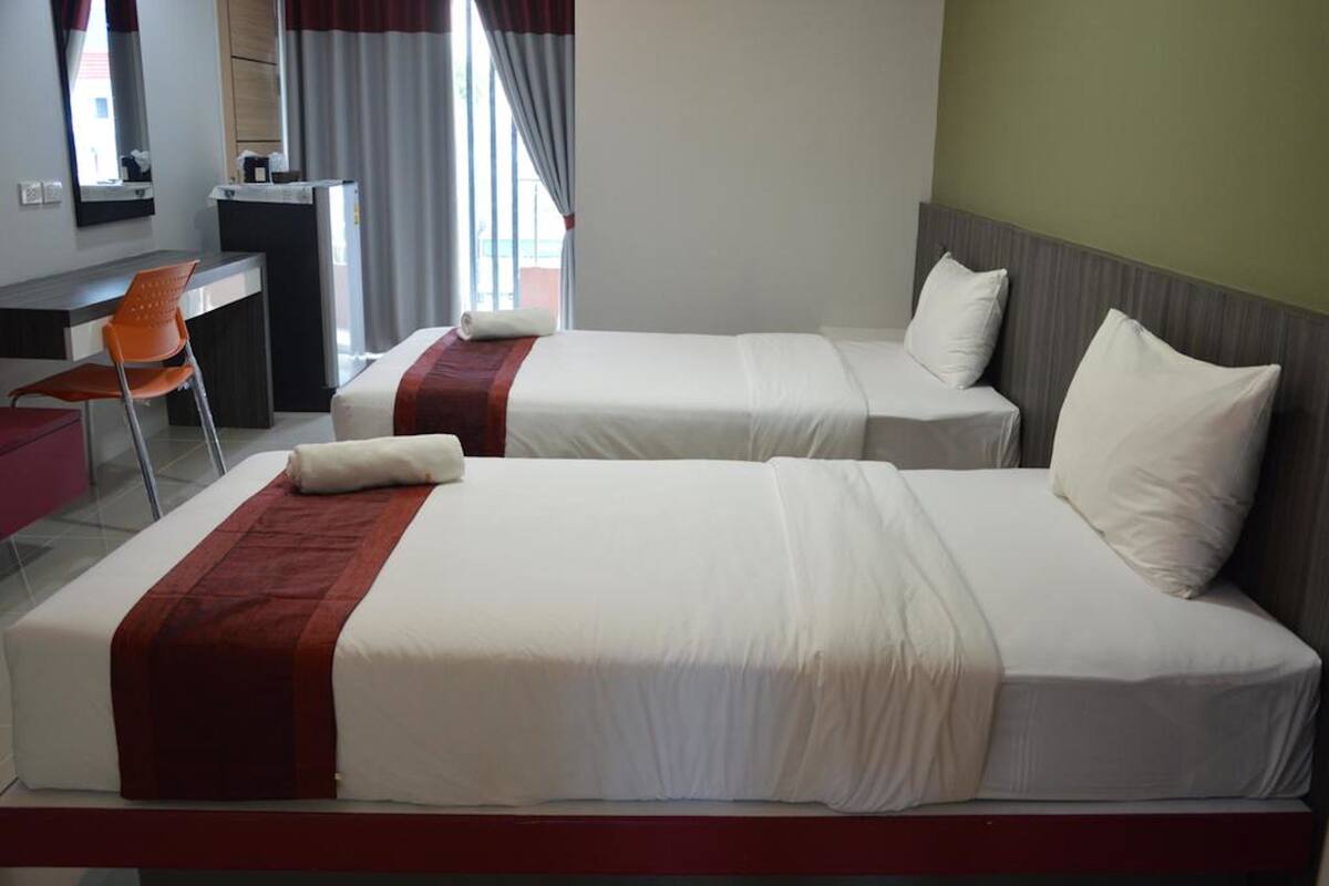 Ein Hotelzimmer mit zwei Betten, einem Schreibtisch und einem Stuhl.