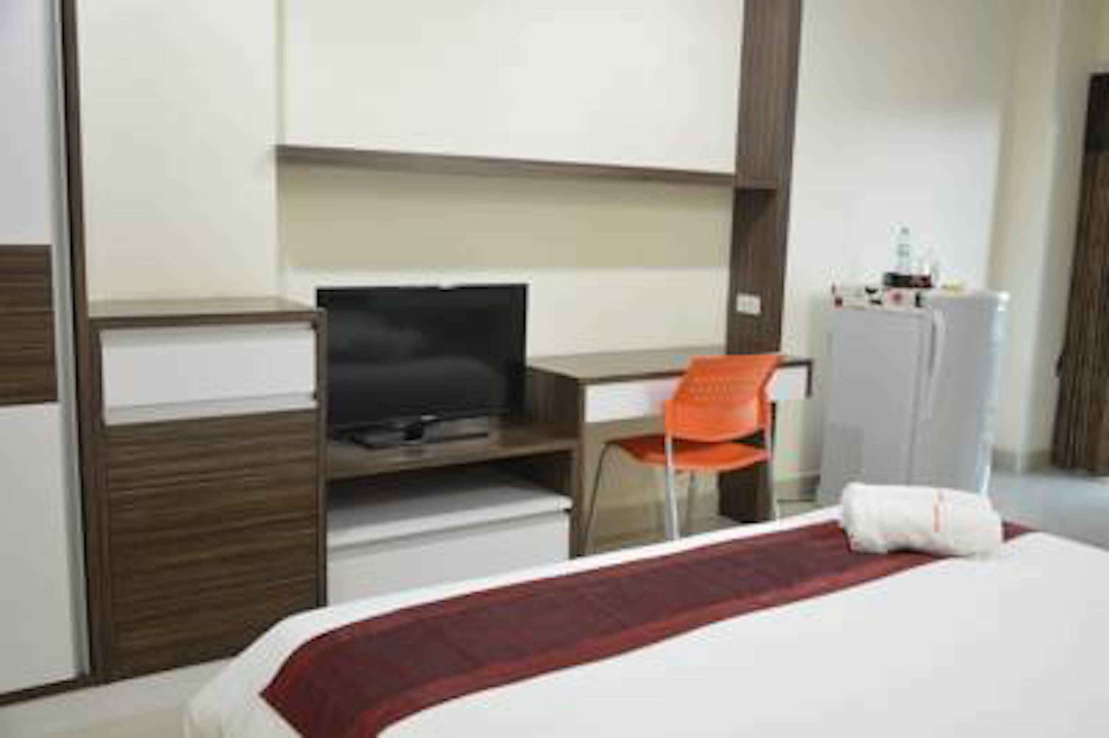A hotel room with a bed, a TV, a desk, and a chair.