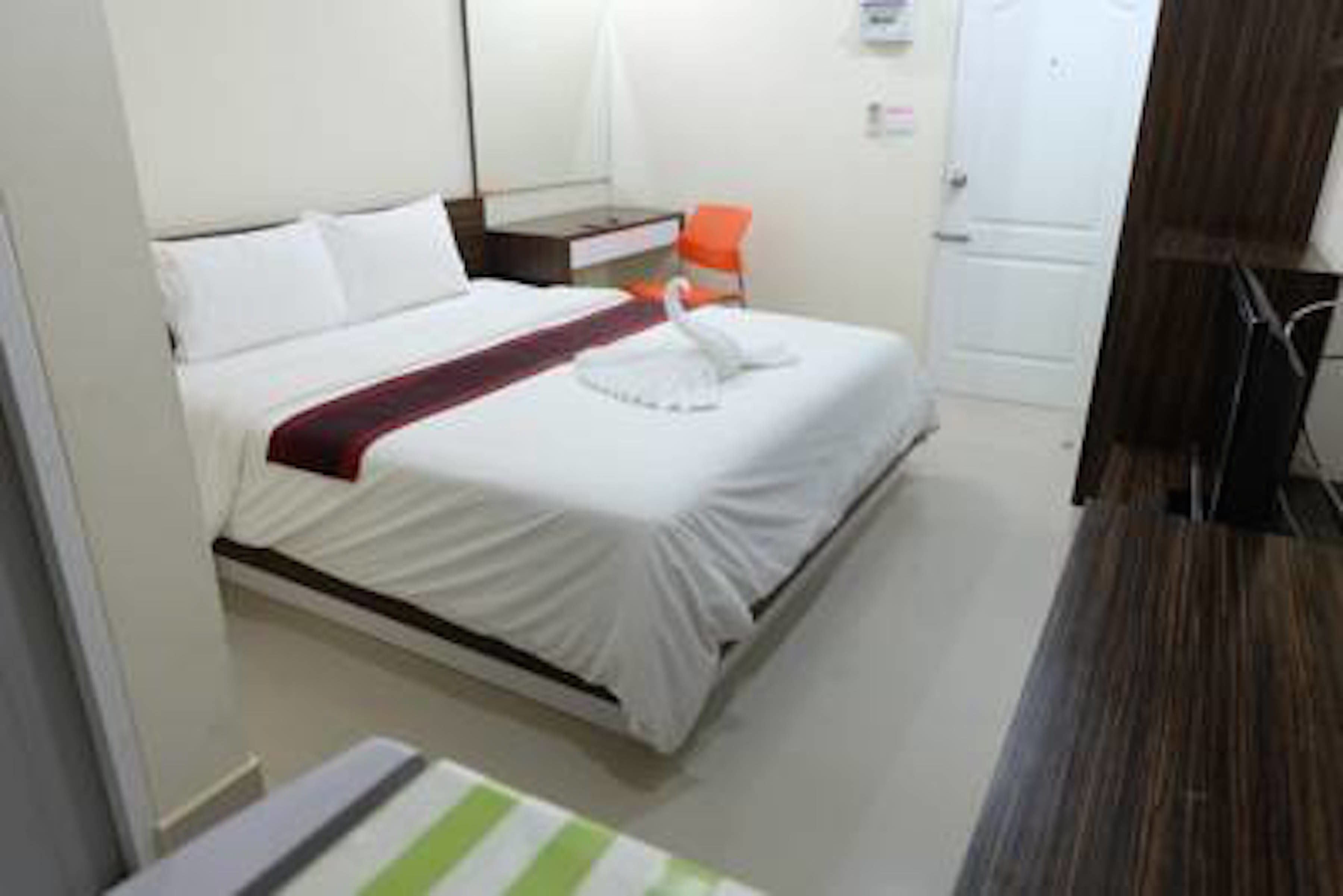 Ein Hotelzimmer mit Bett, Nachttisch, Sessel und Fernseher.