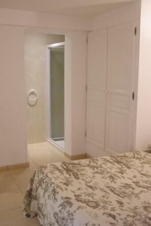 Une chambre à coucher avec un lit, une porte et une salle de bain visible au fond.
