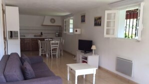 En stue med sofa, fjernsyn og spiseplads med stole og bord.
