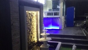 A reception area with a stone wall, a water feature, and a blue-lit counter. - Sritrang Place (Hat Yai)