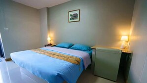 A bedroom with a bed, bedside tables, and a wall-mounted lamp. - Sritrang Place (Hat Yai)