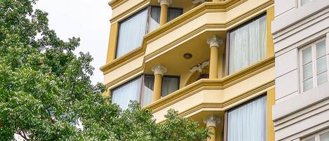 Un immeuble à plusieurs étages, doté d’une façade jaune, de grandes fenêtres et de balcons.