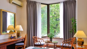 A hotel room with a bed, two chairs, a desk, a small table with a plant, and a window with curtains. - The Spring Hotel (Ho Chi Minh City)