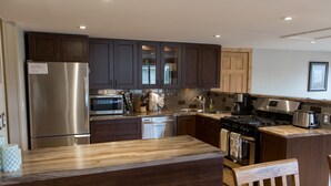 A modern kitchen with dark wooden cabinets, stainless steel appliances, and a wooden countertop.