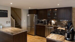A modern kitchen with dark wooden cabinets, stainless steel appliances, and a marble countertop.