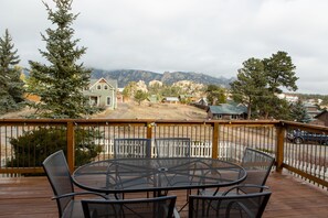 Enjoy a serene view of the surrounding houses and mountains from this deck with a round table and four chairs.