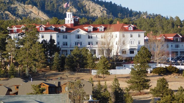 A large white building with a red roof, multiple windows, and a flag on top.