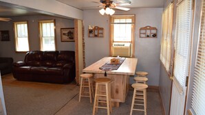 Una sala de estar acogedora con un sofá de cuero, taburetes de madera y una mesa central.