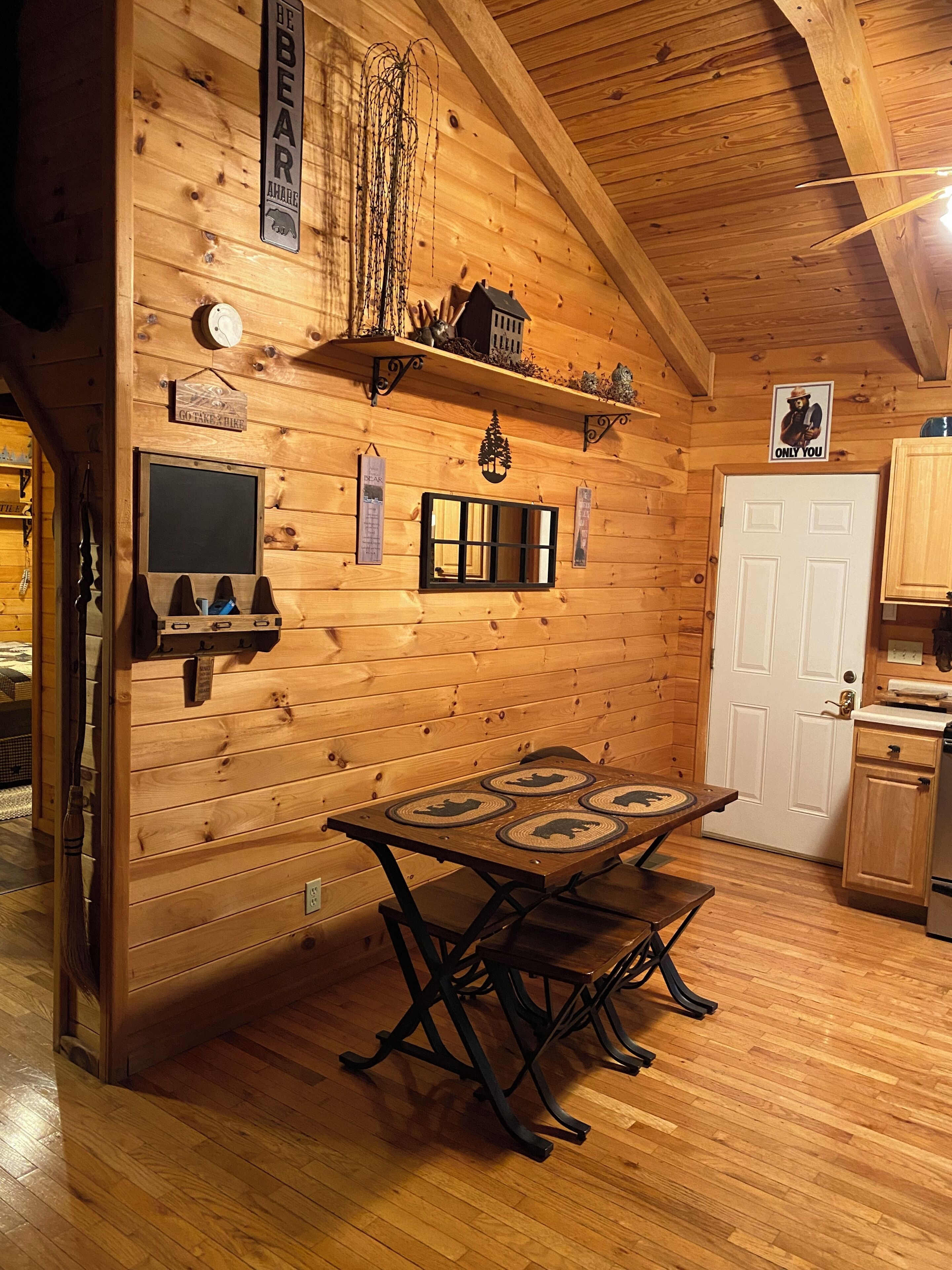 A cozy wooden cabin interior with a dining table, a clock, and a door.