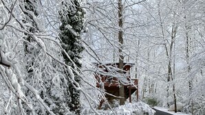 Eine verschneite Straße mit einem hölzernen Chalet auf der linken Seite.