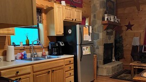 Eine Küche mit Holzausstattung, einem Kühlschrank, einer Kaffeemaschine und einem steinernen Kamin.
