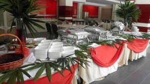 Ein reichhaltiges Buffet mit mehreren Tischen, weißen Tischdecken und roten Vorhängen.