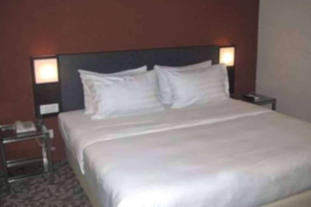 Une chambre d’hôtel avec un grand lit, deux tables de chevet et une petite table d’appoint.