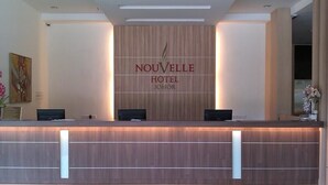 Ein Hotel-Rezeptionstresen mit Holzvertäfelung und einem Schild mit der Aufschrift 'NOUVELLE HOTEL JOHOR'.