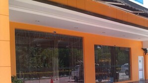 Ein Gebäude mit großen Glastüren, einem Blumentopf und freiem Blick auf die Straße.