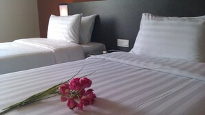 Ein Hotelzimmer mit zwei Betten, einem Kopfteil und einem Nachttisch mit Lampe.