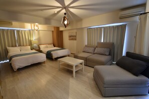 Una habitación de hotel moderna con dos camas, un sofá, una mesita de café y un ventanal con cortinas.