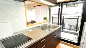 A modern kitchen with a built-in stove, a sink, and wooden cabinets. - Very Hotel Dotonbori (Osaka)