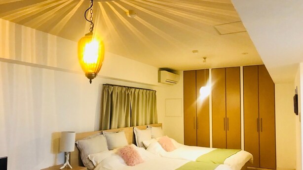 A bedroom with a bed, nightstands, a lamp, a wardrobe, and an air conditioning unit. - Very Hotel Dotonbori (Osaka)